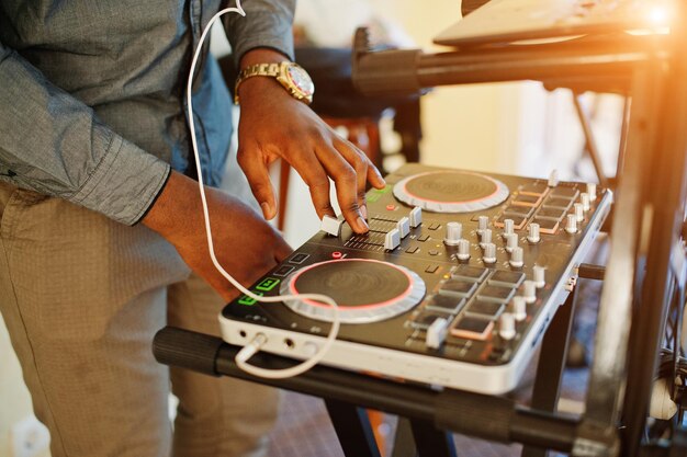 Afro-Amerikaanse dj in enorme witte koptelefoon die muziek maakt op mengpaneel