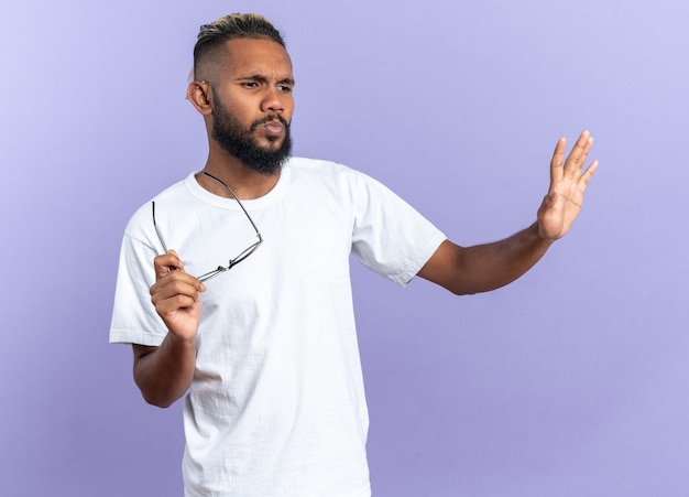 Afro-amerikaanse jongeman in wit t-shirt die ontevreden opzij kijkt