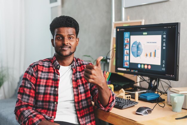 Afro-Amerikaanse jongeman werkt thuis en toont duim voor goed werk op de achtergrond van een bureau