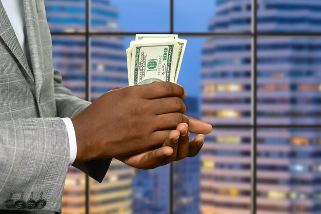 Afro-amerikaanse kantoormanager met salaris. megalopolis zakenman houdt geld vast. verwarm je zak. fris en knapperig.