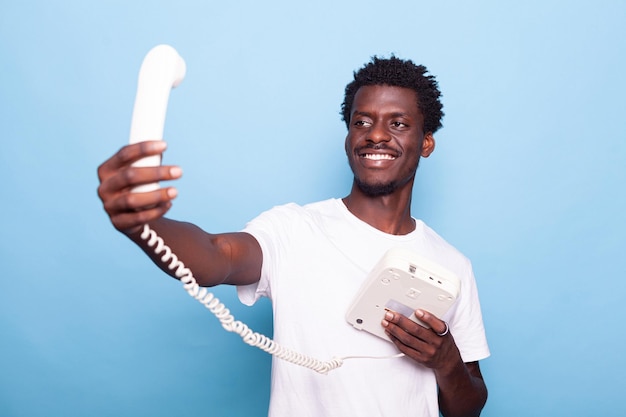 Afro-amerikaanse man die doet alsof hij selfie maakt op een oude vaste telefoon