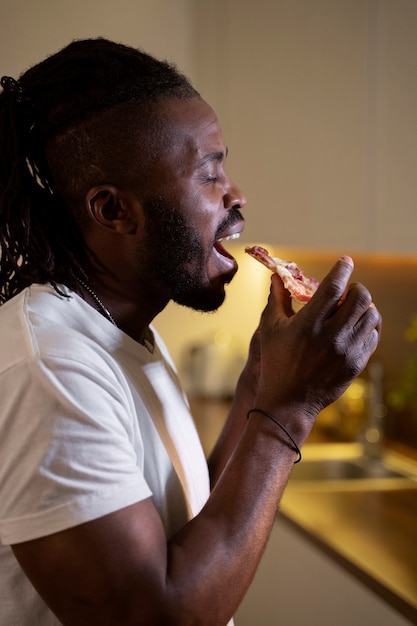 Afro-Amerikaanse man die 's avonds laat pizza eet