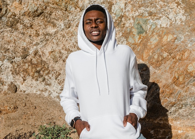 Gratis foto afro-amerikaanse man in witte hoodie poseren buiten fotoshoot