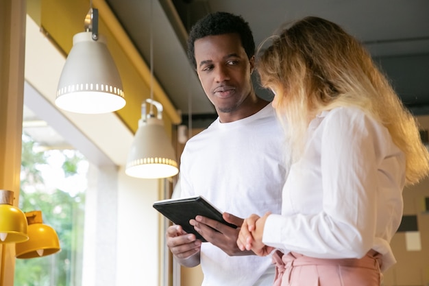 Afro-amerikaanse man kijken naar blonde client en tablet te houden