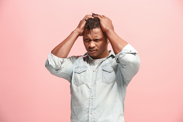 Afro-Amerikaanse man met hoofdpijn. Geïsoleerd over roze.