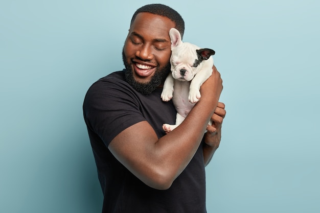 Afro-Amerikaanse man met zwarte T-shirt en kleine hond te houden