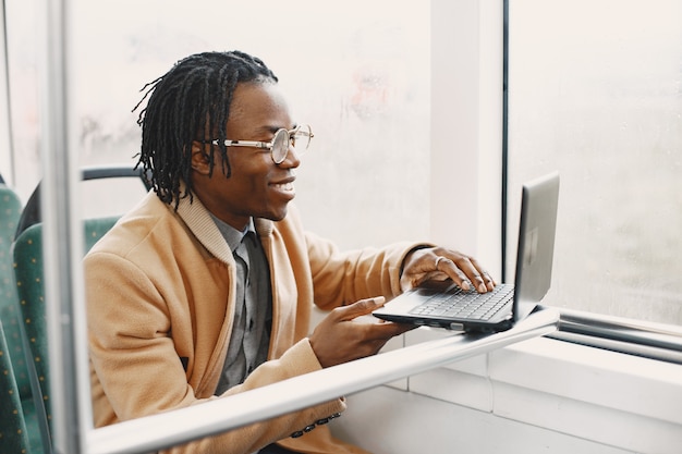 Afro-amerikaanse man rijden in de stadsbus. man in een bruine jas. man met een laptop.