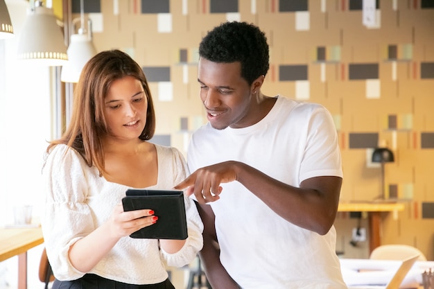 Gratis foto afro-amerikaanse man wijzend op tablet in handen van collega's