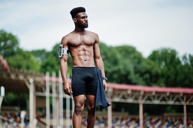 Afro-Amerikaanse mannelijke atleet sexy sport blote torso man met running sport arm case voor mobiele telefoon gesteld op stadion