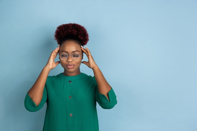 Afro-amerikaanse mooie jonge vrouw portret op blauwe muur emotioneel en expressief