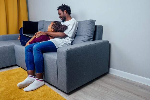 Afro-amerikaanse ouple in woonkamer met behulp van laptop en glimlachen. Premium Foto