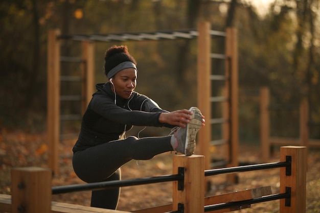 Afro-Amerikaanse sportvrouw die rekoefeningen doet in de buitengymnastiek in de natuur
