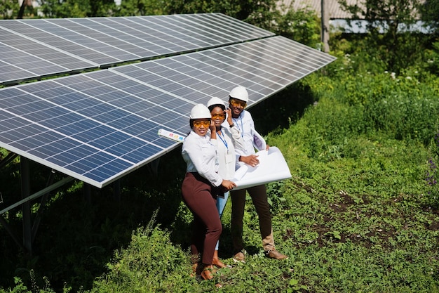 Gratis foto afro-amerikaanse technicus controleert het onderhoud van de zonnepanelen groep van drie zwarte ingenieurs die bijeenkomen op het zonnestation