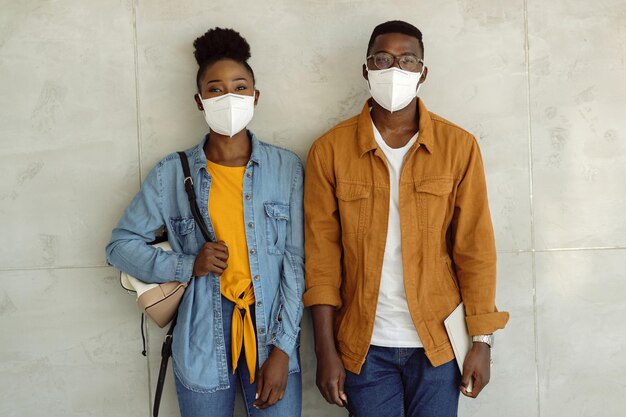 Afro-Amerikaanse universiteitsstudenten met beschermende gezichtsmaskers tegen de muur