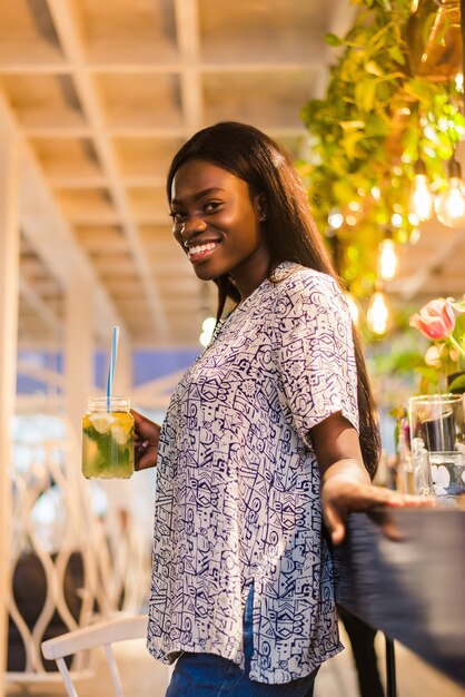 Afro-Amerikaanse vrouw cocktail limonade drinken in café aan de bar.