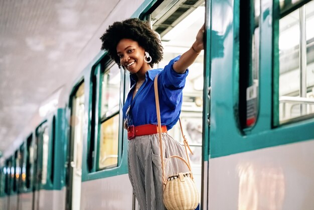 Afro-Amerikaanse vrouw die aan een treindeur hangt