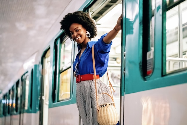 Afro-Amerikaanse vrouw die aan een treindeur hangt