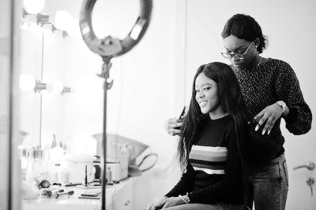 Afro-Amerikaanse vrouw die kapper of haarstylist toepast bij schoonheidssalon