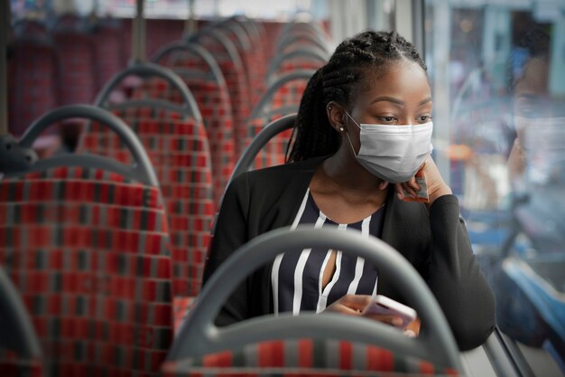 Afro-Amerikaanse vrouw die masker op de bus draagt tijdens het reizen met het openbaar vervoer in de nieuwe normaal