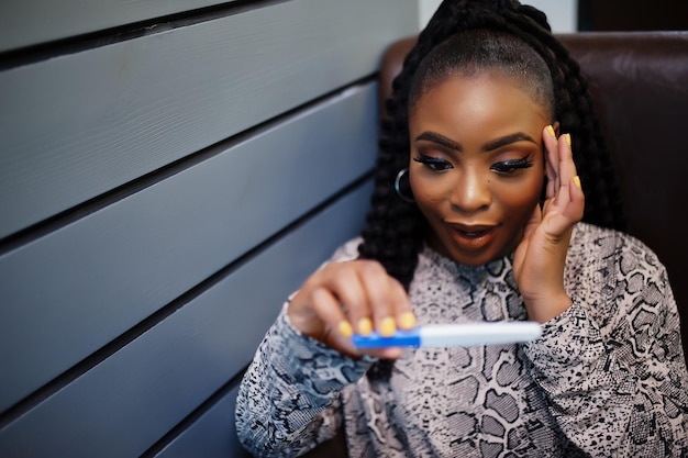 Afro-Amerikaanse vrouw die verrassing voelt, houdt zwangerschapstest vast