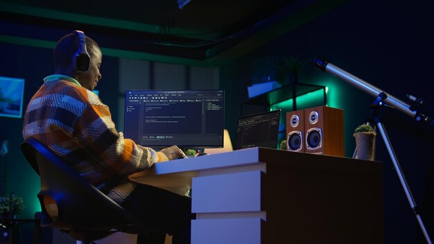 Afro-Amerikaanse werknemer aan het bureau die een personal computer gebruikt voor het programmeren