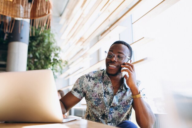 Afro-Amerikaanse zakenman met telefoon en laptop in een café