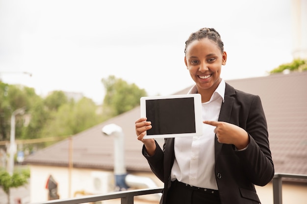 Afro-Amerikaanse zakenvrouw in kantoorkleding glimlachend, ziet er zelfverzekerd en gelukkig, succesvol uit
