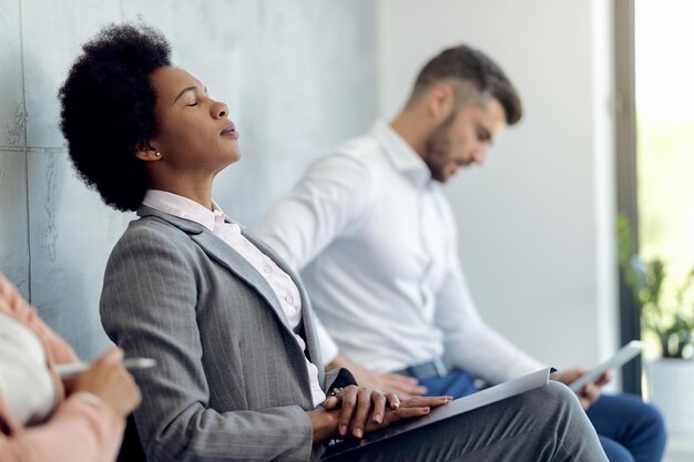 Afro-Amerikaanse zakenvrouw probeert zich te concentreren tijdens het wachten op een sollicitatiegesprek