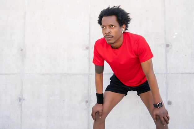 Afro atletische man rust na het sporten buitenshuis. Sport en gezonde levensstijl concept.