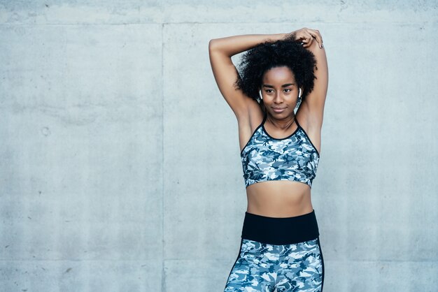 Afro atletische vrouw die zich uitstrekt en opwarmt voor de training buitenshuis.