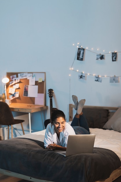 Gratis foto afstandsschot glimlachende vrouw die aan laptop in bed werkt