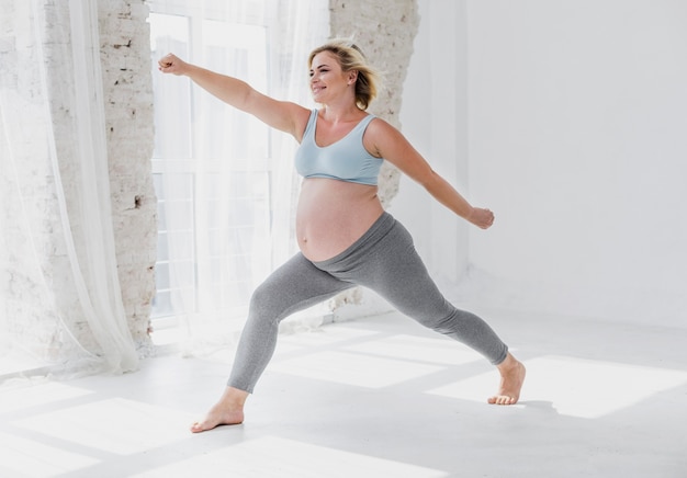 Afstandsschot vrij zwangere vrouw die wat yoga doet