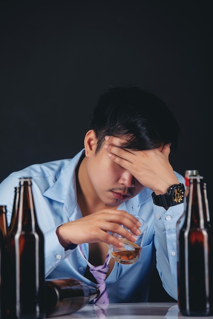 alcoholische Aziatische man die whisky met veel flessen drinkt