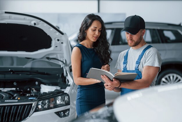 Alles wat ik heb gedaan. Vrouw in de autosalon met werknemer in blauw uniform die haar gerepareerde auto terugneemt