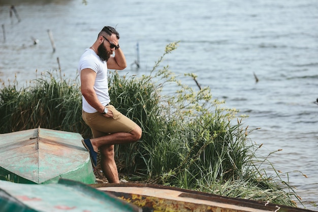 American Bearded Man kijkt op de oever van de rivier in een blauwe jas