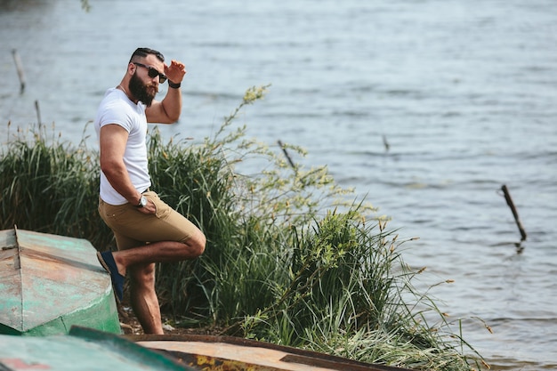 American Bearded Man kijkt op de oever van de rivier in een blauwe jas