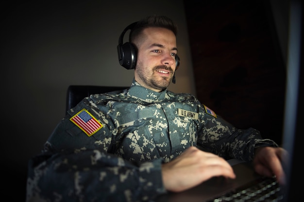 Amerikaanse soldaat met hoofdtelefoon voor de laptop die in het inlichtingencentrum werkt