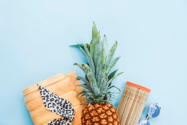 Ananas dichtbij handdoek en mat met zonnebril