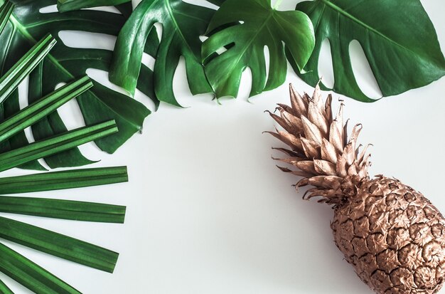 Ananas gouden kleur met tropische bladeren op witte achtergrond, zomer concept