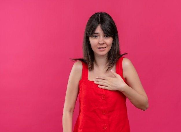 Angstig jong Kaukasisch meisje die hand op borst houden en camera op geïsoleerde roze achtergrond met exemplaarruimte bekijken