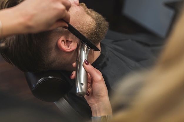 Anonieme vrouw die baard van de mens in orde maakt