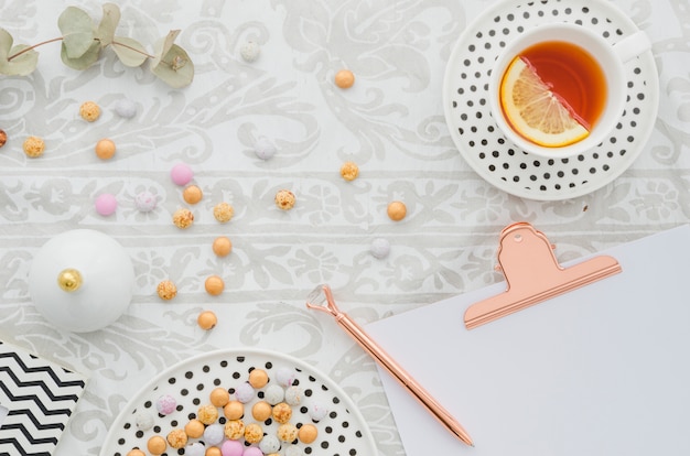 Antieke pen op klembord met snoepjes en gember citroenthee cup op tafellaken