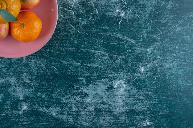 Appels en mandarijnen op een bord, op de marmeren tafel.