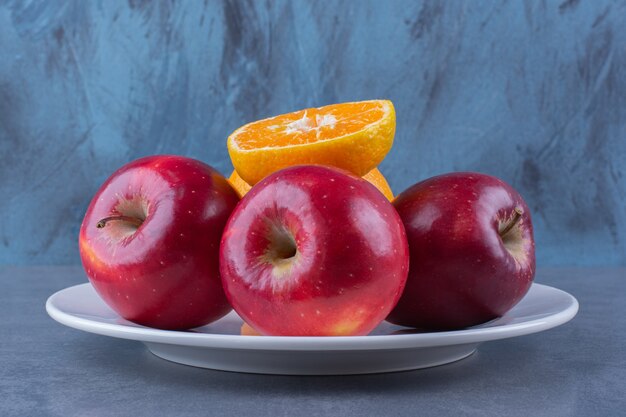 Appels en sinaasappel op plaat op het donkere oppervlak