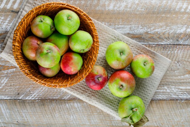 Appels in een rieten mand op houten en keukendoek.