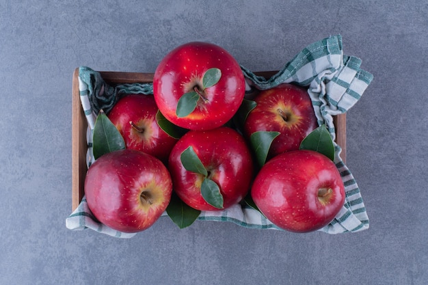 Appels met bladeren op een handdoek op een doos op het donkere oppervlak