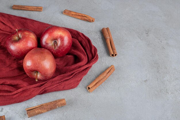 Appels omgeven met kaneelsneden op marmeren oppervlak.