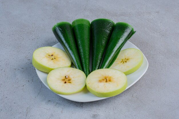 Appelschijfjes en appel op smaak gebrachte zure snack op een schotel op marmeren achtergrond.