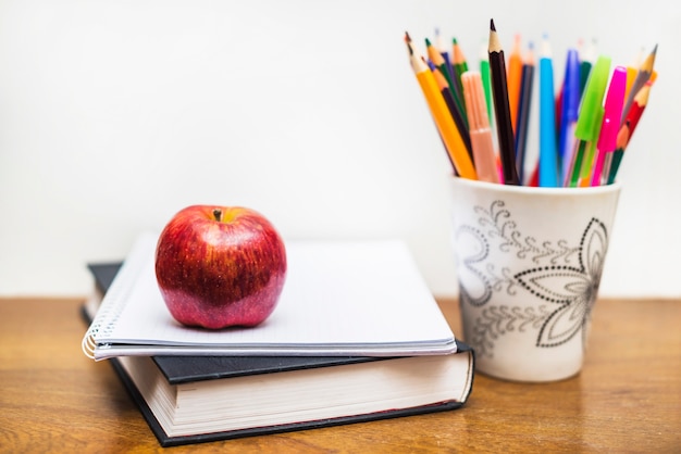Apple en potloden dichtbij notitieboekje en boek
