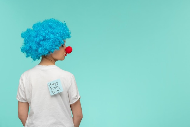 April dwazen dag meisje ziet er goed uit met blauwe sticker tshirt rode neus clown kostuum blauw haar